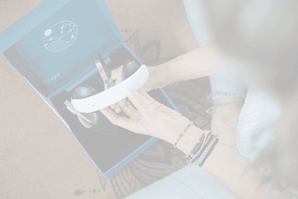 Eine Frau hält ein tDCS-Headset von Flow Neuroscience über einer geöffneten Produktverpackung in den Händen.